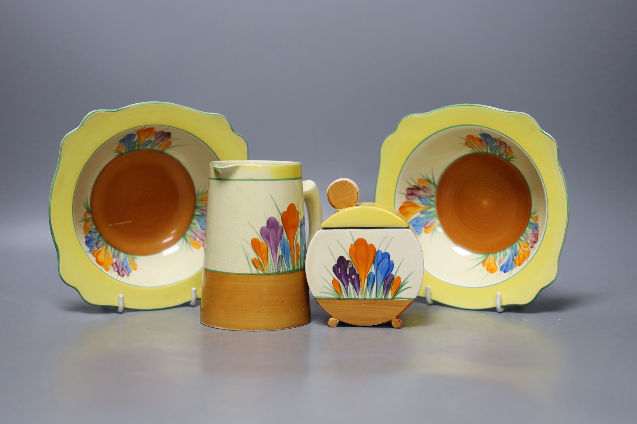 A Clarice Cliff crocus jug, 2 dishes and a jam pot and cover